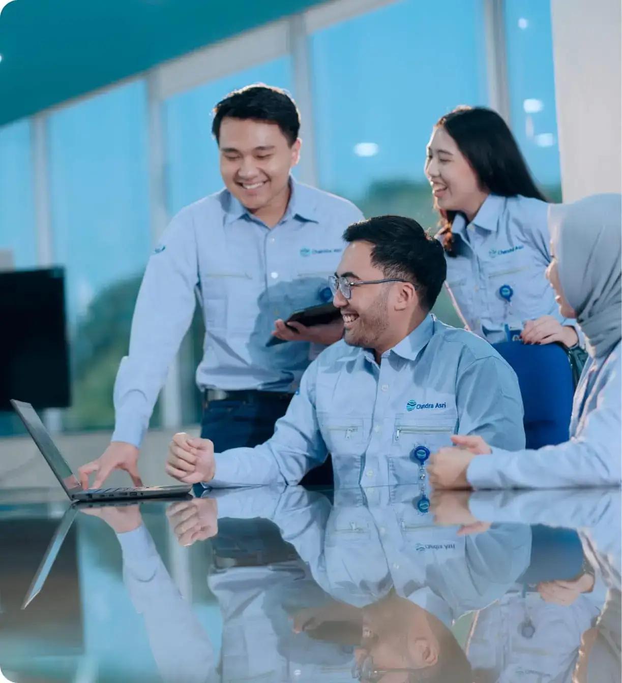 A team of professionals discussing with enthusiasm, wearing Chandra Asri uniforms in the workspace
